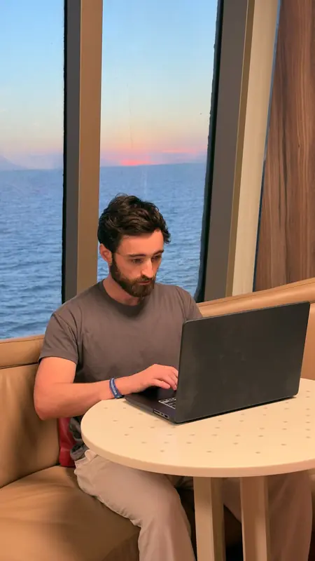 Patrick trabajando desde su laptop en un crucero al atardecer en el mar