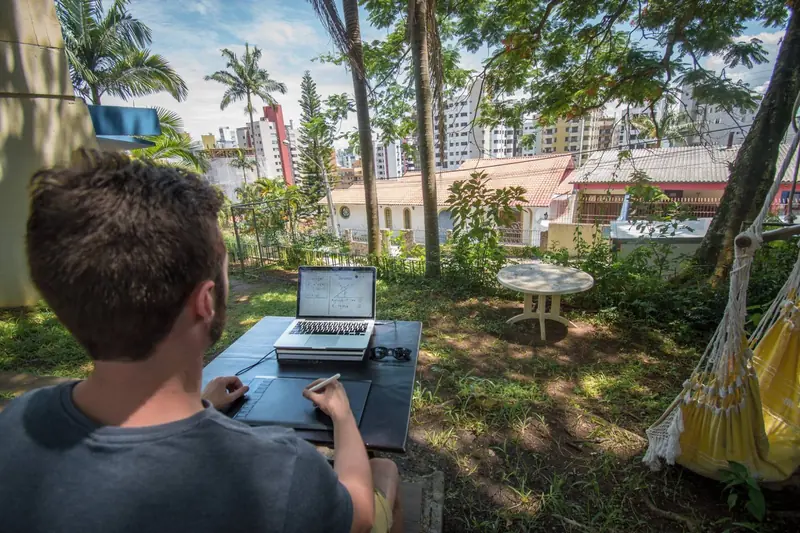Patrick trabajando con su laptop en un jardín en Florianópolis, Brasil